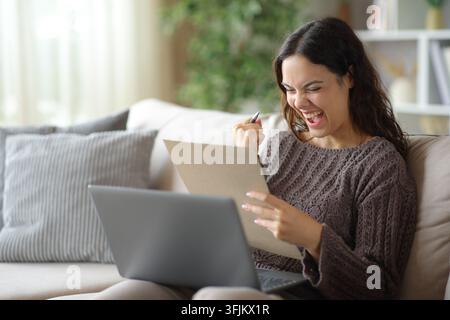 Excited telecommuter checking documents working online sitting on a couch at home Stock Photo
