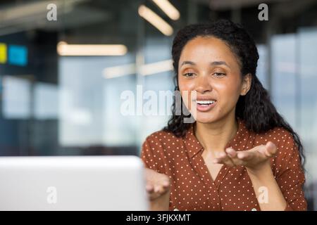 Remote work communication and video call, young woman using laptop for virtual meeting in office. Stock Photo