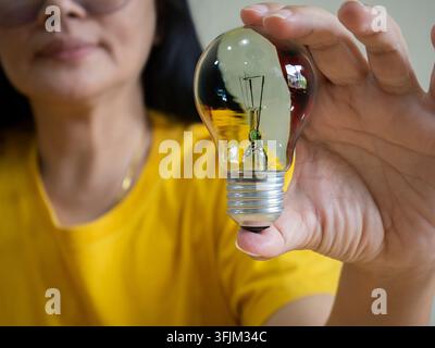 An Asian women hand holding light bulb with smile. concept of new ideas with innovation and creativity. Stock Photo