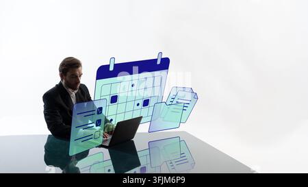 Organized man manages deadlines on laptop with floating calendar panels in minimalist office with determined focus Stock Photo
