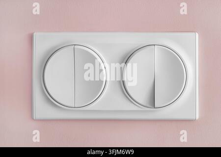 Four buttons light switch on pink painted wall closeup Stock Photo