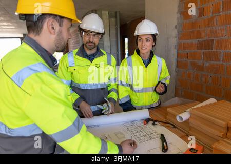 Construction team examining blueprints on table Stock Photo