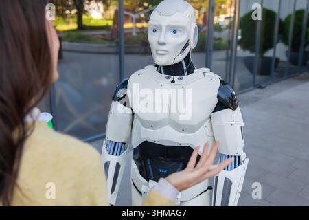 Futuristic robot looking at woman making hand gesture Stock Photo