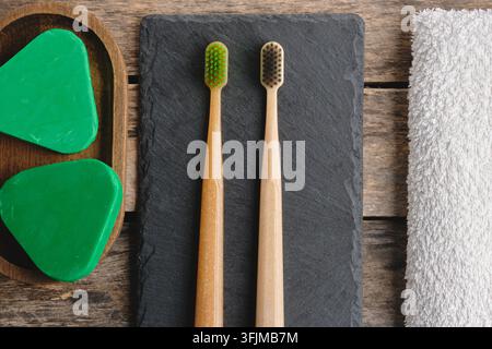 Sustainable bathroom composition with bamboo toothbrushes, solid shampoo in tray, and towel Stock Photo