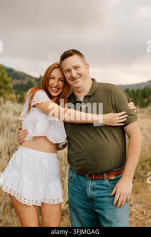 Happy young woman laughing and hugging her father outdoors Stock Photo
