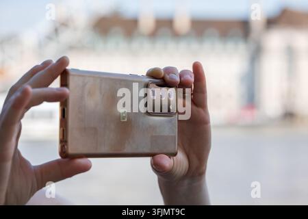 Detailed close-up shot of a person holding a bronze smartphone with a multi-lens camera module in landscape mode to take a photograph in soft daylight Stock Photo