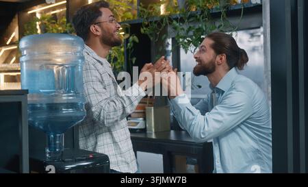Arabian Caucasian men in office two diversity business friends guys businessmen discussing amazing news happy laughing excited talk Indian partners Stock Photo