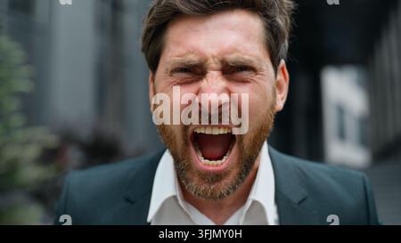 Close up furious stressed middle-aged Caucasian business man looking at camera yelling with rage stress failure work bankruptcy problem screaming Stock Photo