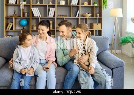 Happy parents with children bonding on sofa at home, smiling and laughing together indoors Stock Photo