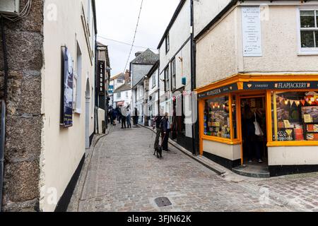 Traditional narrow streets and stone buildings in the historic centre of St Ives, Cornwall, England, with colourful bunting overhead and independent Stock Photo