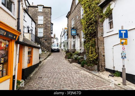 Traditional narrow streets and stone buildings in the historic centre of St Ives, Cornwall, England, with colourful bunting overhead and independent Stock Photo