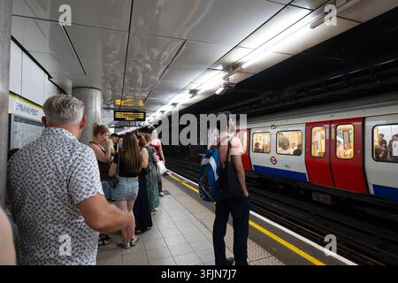 London, England, United Kingdom, August 14, 2026. Passengers standing on the platform at Embankment station waiting for a London Underground tube trai Stock Photo