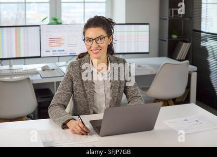Confident business analyst woman working on laptop in office, finance audit data Stock Photo