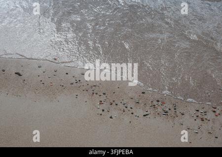 Gentle Wave Meeting a Pebbly Sandy Shore at an Angle Stock Photo