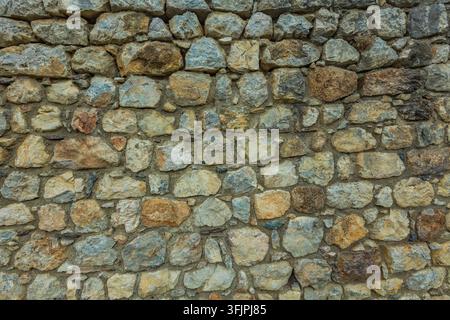 Close-up of a traditional masonry wall built from irregular natural stones in gray, beige and brown tones. Detailed rustic texture ideal for architect Stock Photo
