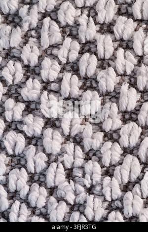 Close up of white loop pile yarn on gray woven textile surface, showing soft fiber texture, dense pattern, and neutral abstract background. Stock Photo