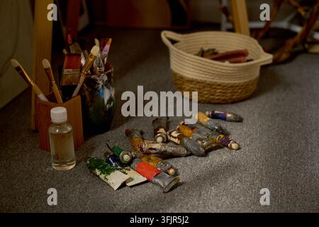 Oil Paint Tubes with Brushes on Floor in Art Studio Stock Photo