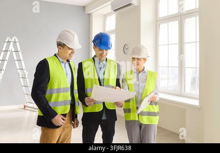 Architects and engineers planning safety review with blueprints at renovation site Stock Photo