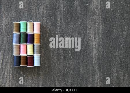 Set of spools of colored threads for sewing and fashion design on vintage wooden gray background Stock Photo