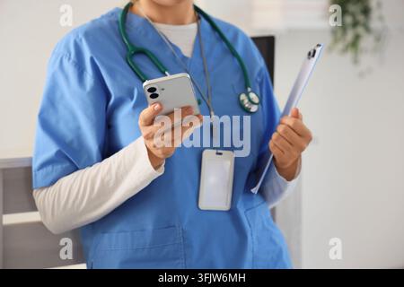 Telemedicine and digital healthcare, nurse using smartphone for patient communication and medical records in a modern hospital clinic environment Stock Photo