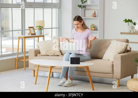 Technical support and internet connection issues, frustrated woman with laptop experiencing home network failure or router problem in living room Stock Photo