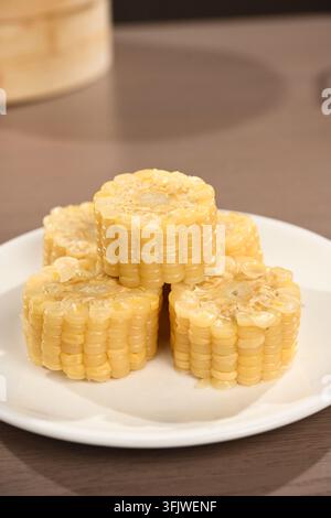 Yellow Corn Segments on White Plate with Bamboo Steamer Background Stock Photo