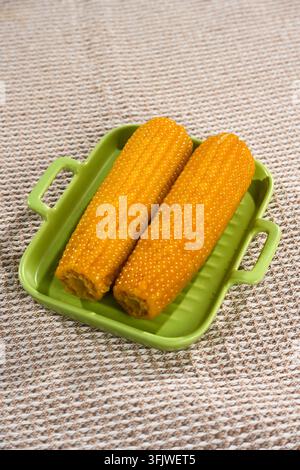 Whole Yellow Corn Cobs on Green Handled Tray, Woven Linen Background Stock Photo