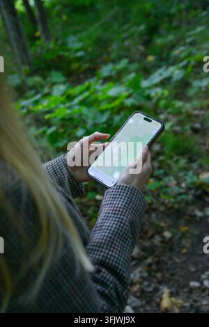 Woman using a smartphone map for navigation on a forest hiking trail, highlighting outdoor adventure, route planning, travel technology, GPS wayfindin Stock Photo