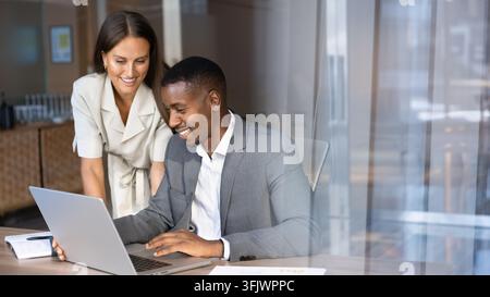 Multiethnic team members working together using laptop in corporate office Stock Photo