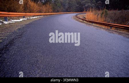 Hazardous driving conditions on a winding icy road following a snow fall in a remote forest area of New South Wales, Australia. Stock Photo