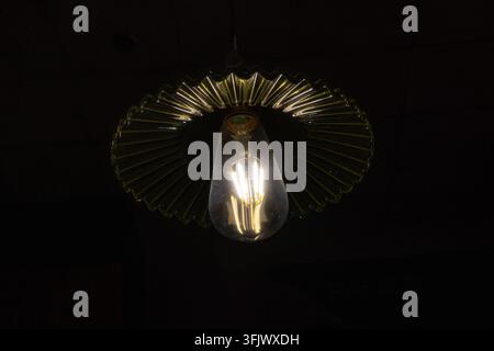 Close-up of vintage filament bulb glowing in dim light Stock Photo