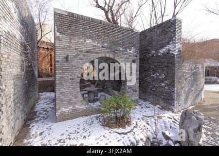 Courtyard of Red Brick Art Museum in Beijing with grey brick moon gate, stone table and stone benches Stock Photo