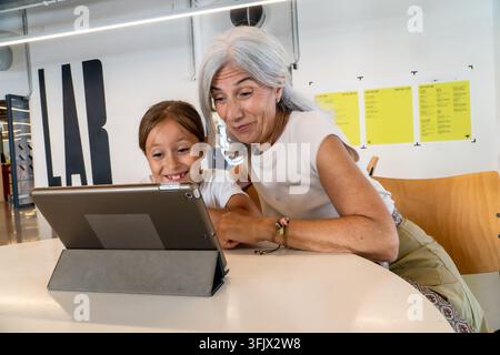 Grandmother and granddaughter bonding with tablet, learning technology together Stock Photo