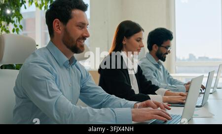 Diverse multiethnic business team working laptops in office businessmen businesswoman typing computers focused smiling colleagues tech support staff Stock Photo