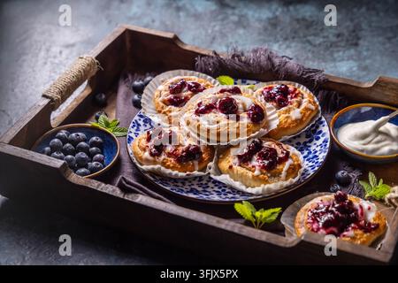 Freshly baked blueberry cinnamon rolls with sweet glaze served on a rustic wooden breakfast tray Stock Photo