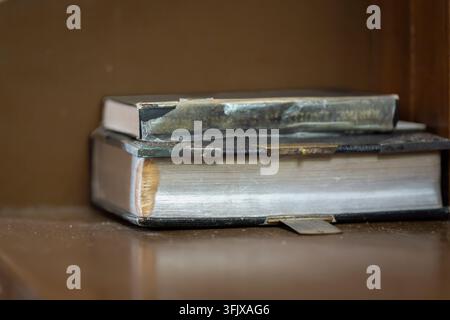 An old Bible resting on a worn wooden church pew, its aged leather cover, weathered pages and traditional binding revealing years of use. Stock Photo