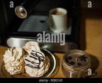 Fresh marshmallows, coffee cup, and candle by espresso machine Stock Photo