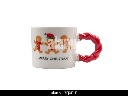 A white ceramic Christmas mug featuring gingerbread man figures, a red twisted handle, and the text Merry Christmas isolated on a white background. Stock Photo