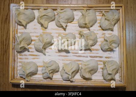 Overhead shot of raw dumplings on bamboo tray Stock Photo