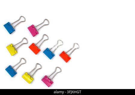 A group of colored metal paper clips is arranged diagonally on a white background, leaving space for text. Stock Photo