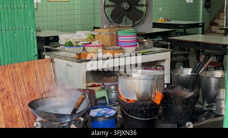 BANGKOK, THAILAND - MAR 15, 2026: A street food restaurant kitchen in Bangkok, Thailand, showing boiling pots cooking on traditional charcoal stoves w Stock Photo