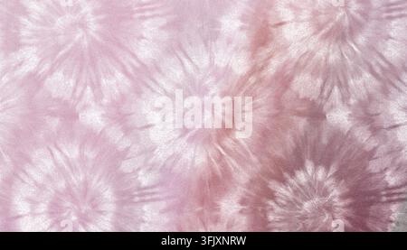 A close-up of a soft pink and rose gold tie-dye textile featuring repeating starburst patterns with a gentle glittery shimmer across the surface. Stock Photo