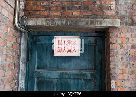 Close-up of blue wooden door and electrical distribution weight label on red brick wall Stock Photo