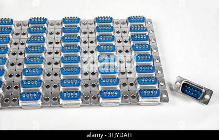 A circuit board shows many blue connectors in rows. One connector is placed separately to the right. The setting is simple and focused. Stock Photo