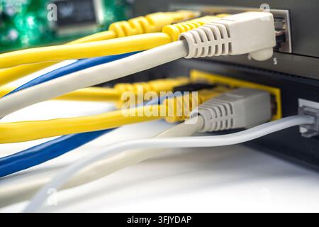 Several networking cables link to a router in a home office setting. The image shows close-up details of the cables. Stock Photo