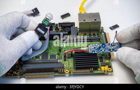 Hands work on a circuit board with sensors and components for a smart home system. The location is a workshop. Stock Photo