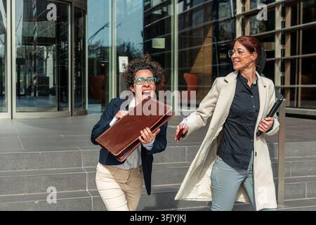 Business women running late to work outside office Stock Photo