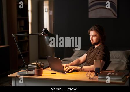 Man Typing on Laptop during Remote Work Late at Night Stock Photo