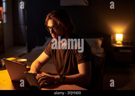 Man with Glasses Working on Laptop at Night during Overtime Stock Photo