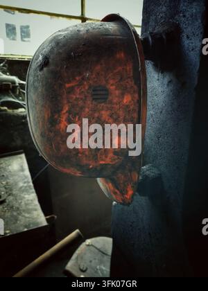 Dirty orange hard hat hanging inside a workshop Stock Photo